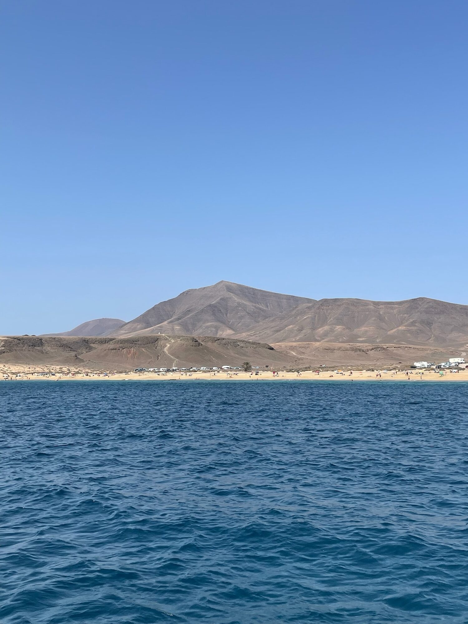 Sandstrand mit Bergen im Hintergrund, gesehen vom Atlantik bei Lanzarote aus.