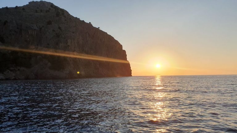 Sonne geht neben einer steilen Felsküste Mallorcas über dem Mittelmeer auf.