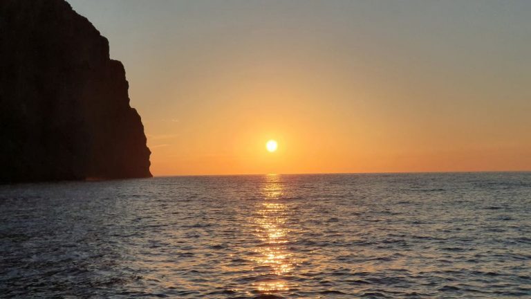 Sonnenuntergang über dem Meer neben einer schroffen Felsküste vor Mallorca.