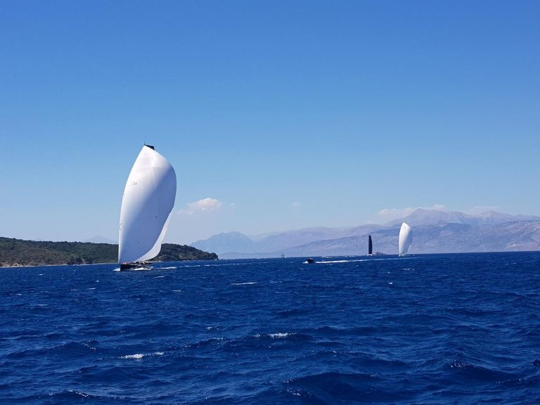 Segelboote mit gesetztem Spinnaker auf dem Ionischen Meer vor der griechischen Küste mit Bergen im Hintergrund.