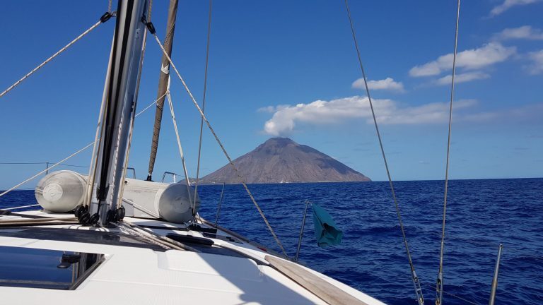 Blick vom Segelboot auf den Vulkan Stromboli mit aufsteigender Rauchwolke, Liparische Inseln.