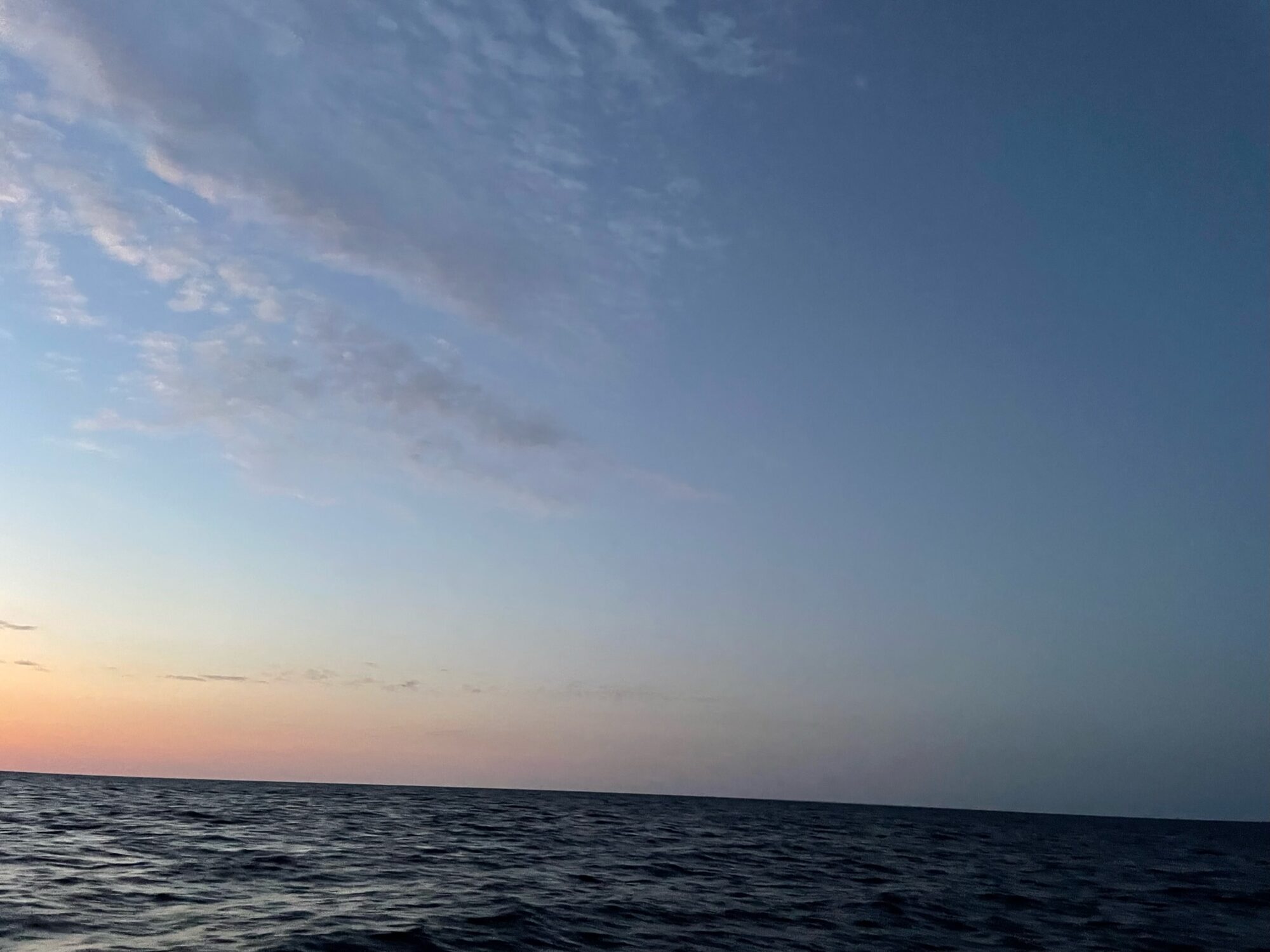 Weite Wasserfläche des Atlantiks unter dämmerndem Himmel mit zartem Wolkenband am Horizont.