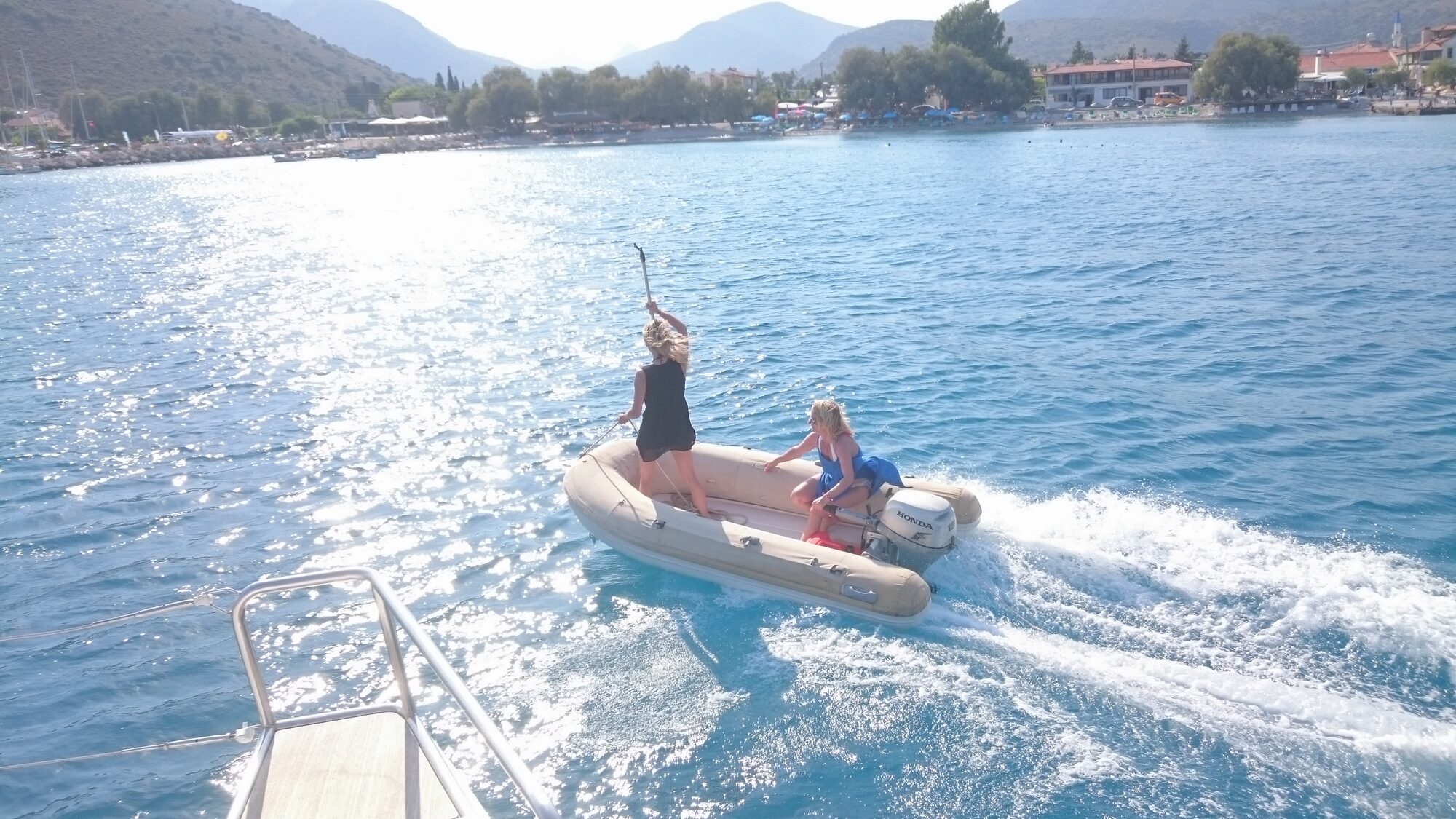 Zwei Frauen fahren mit einem Schlauchboot mit Honda-Außenmotor durch eine türkische Küstenbucht in der Ägäis.