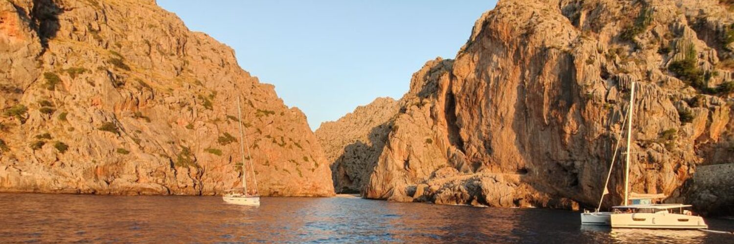 Segelboote ankern zwischen steilen Felswänden einer engen Meeresschlucht auf Mallorca.