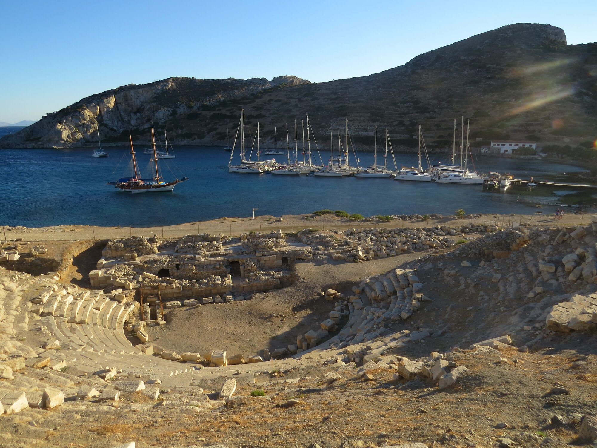 Antikes Amphitheater am Mittelmeer in der Türkei mit Blick auf eine Bucht mit Segelbooten und Yachten vor bergiger Küste.