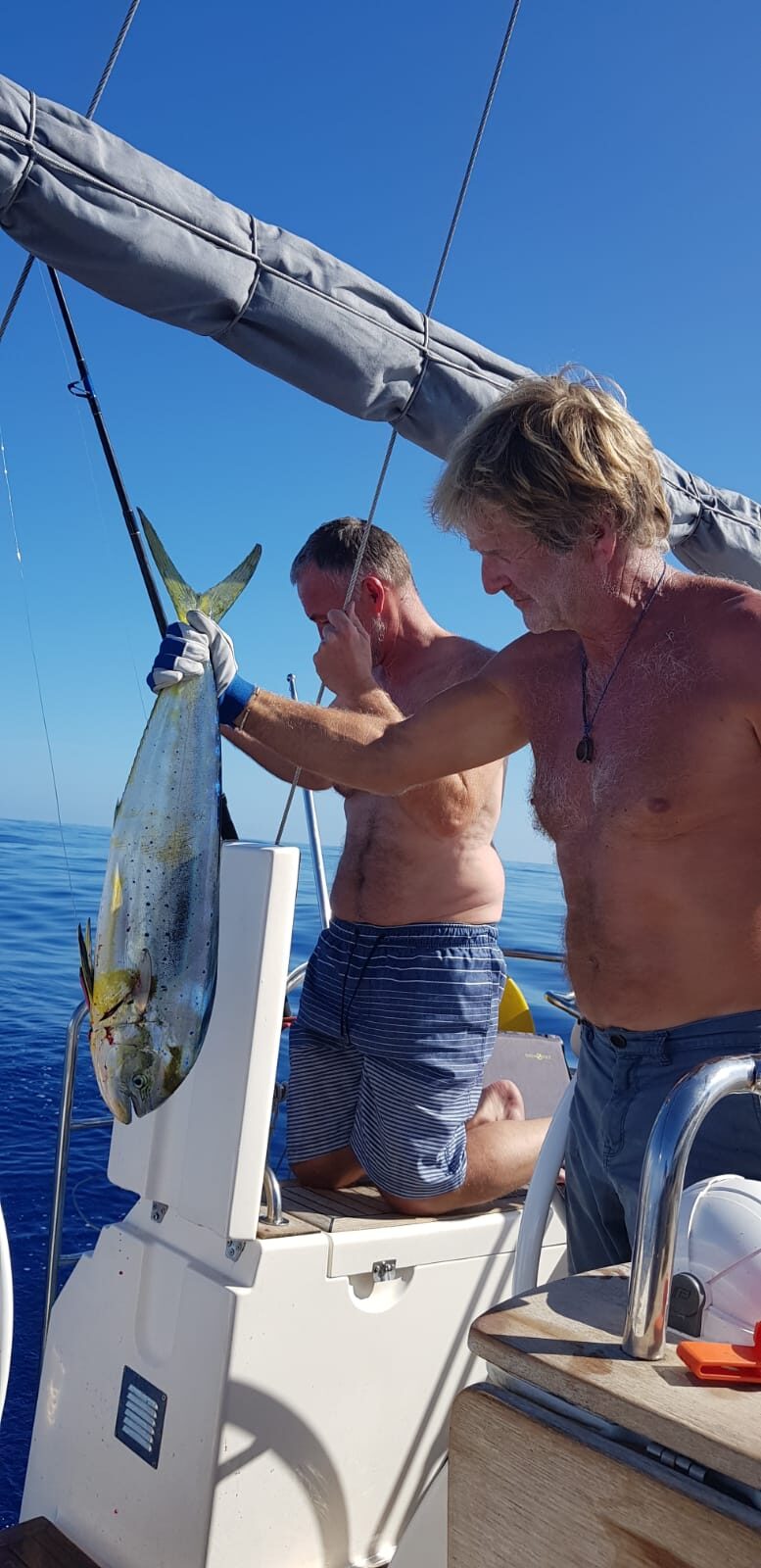 Zwei Männer halten auf dem Segelboot einen frisch gefangenen Fisch auf dem Atlantik.
