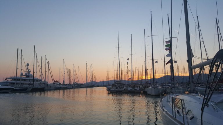 Segelboote und Yachten liegen im Hafen von Kroatien, im Hintergrund Berge bei Sonnenuntergang.