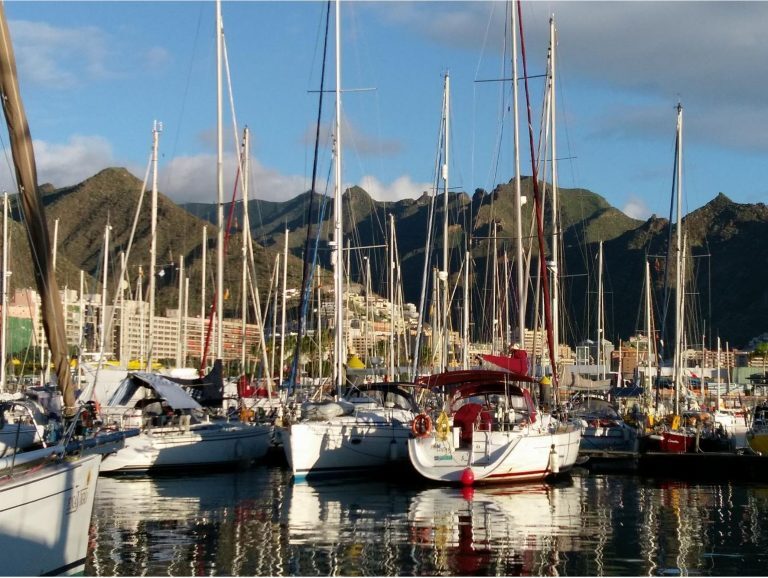 Segelboote liegen im Hafen von Santa Cruz de Tenerife vor Bergen und Häusern der Stadt.