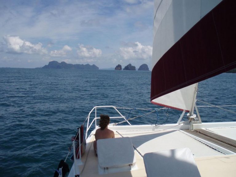 Eine Person sitzt am Bug eines Katamarans und blickt auf Felsinseln in der Phang-Nga-Bucht vor Krabi.