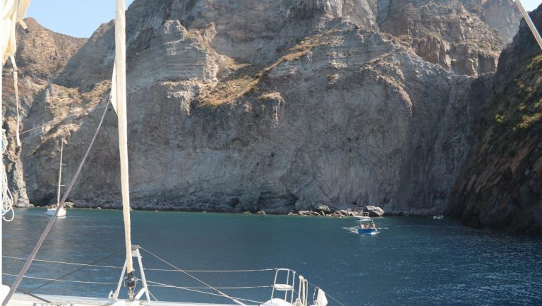 Segelboote ankern in einer Bucht vor steilen Felsklippen der Liparischen Inseln.
