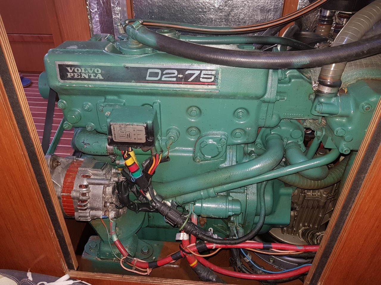 Volvo-Penta-Dieselmotor D2-75 im Motorraum eines Bootes, umgeben von Holzverkleidung, Schläuchen und Kabeln.