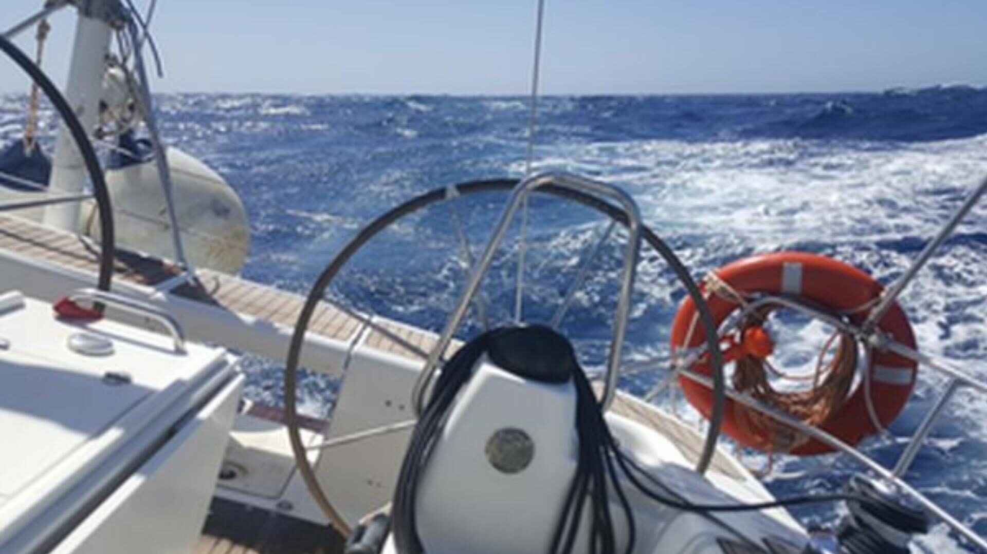 Steuerrad und Rettungsring eines Segelboots auf bewegter See auf dem Atlantik.